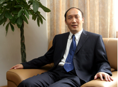 Professor Wei Yang sitting in a brown leather chair, facing to the camera