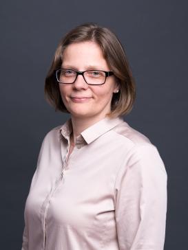 profile picture of Cathleen Paethe (light pink button-up shirt, glasses, half-length hair), dark background 