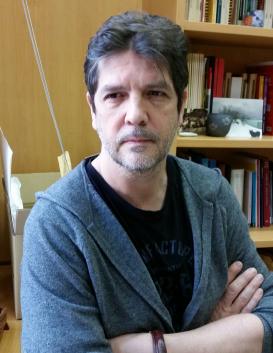 Javier Moscoso with crossed arms in front of a bookshelf