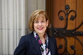 Angela Creager posing in front of an old-fashioned door