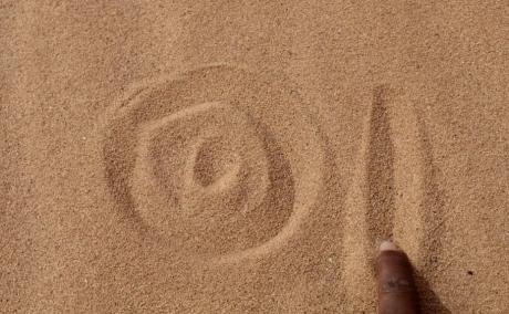 Drawing the project’s logo in the sand.